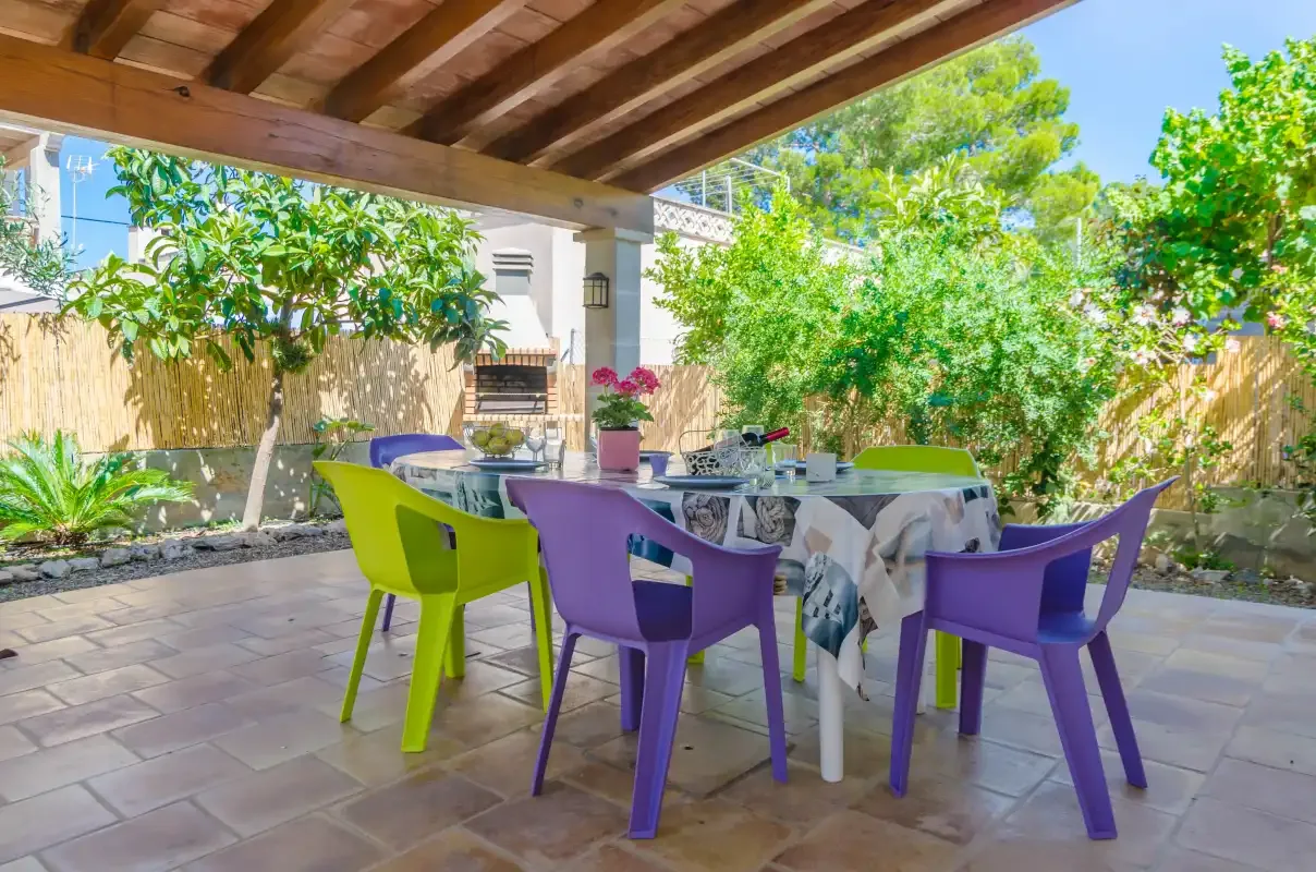 A covered patio dining area with colorful chairs and a table.