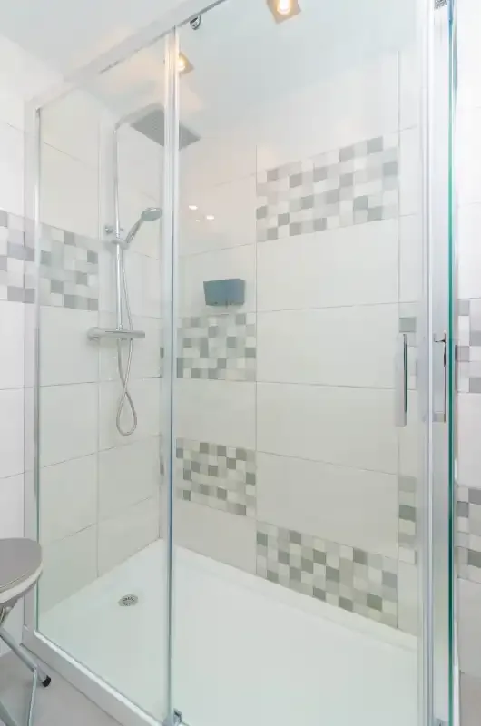 A tiled shower with glass panels and a wall-mounted showerhead.