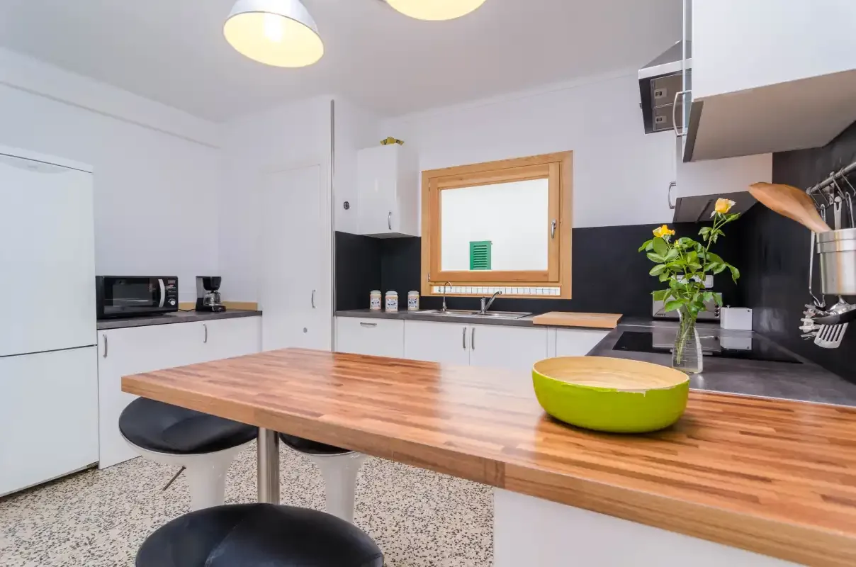 A bright kitchen with a wooden island and white cabinetry.