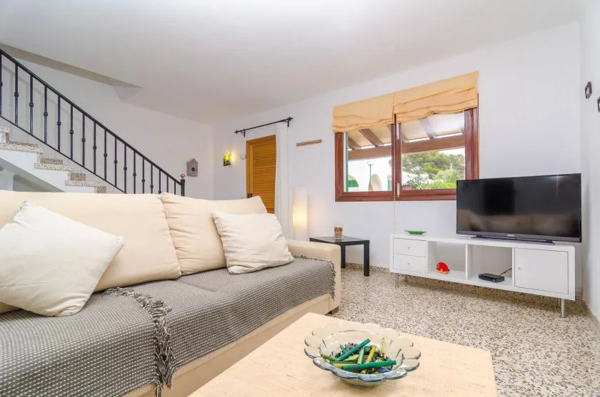 A living room with a sofa, television, and staircase.