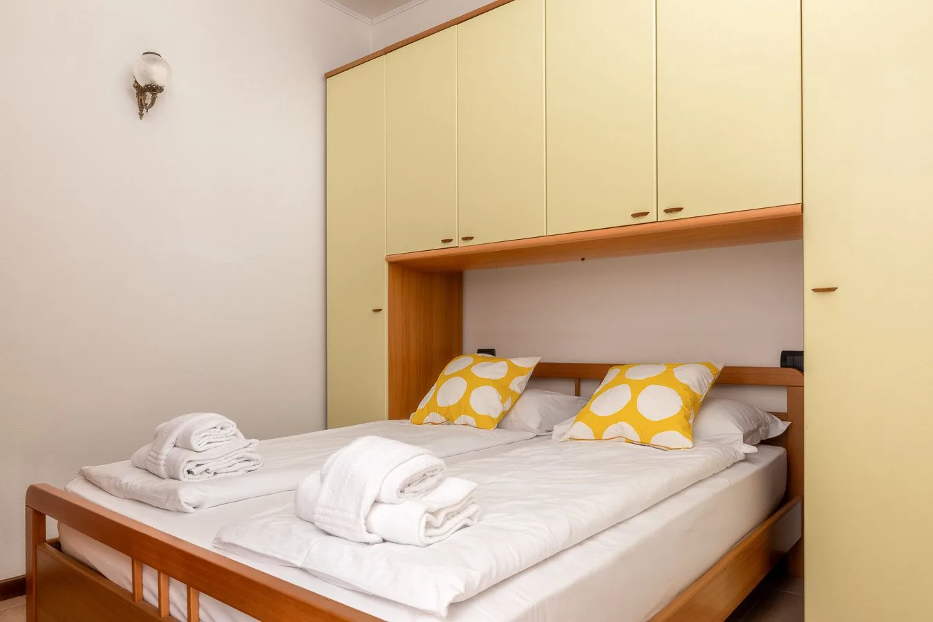 Un dormitorio con una cama doble, almohadas estampadas amarillas y armarios empotrados.