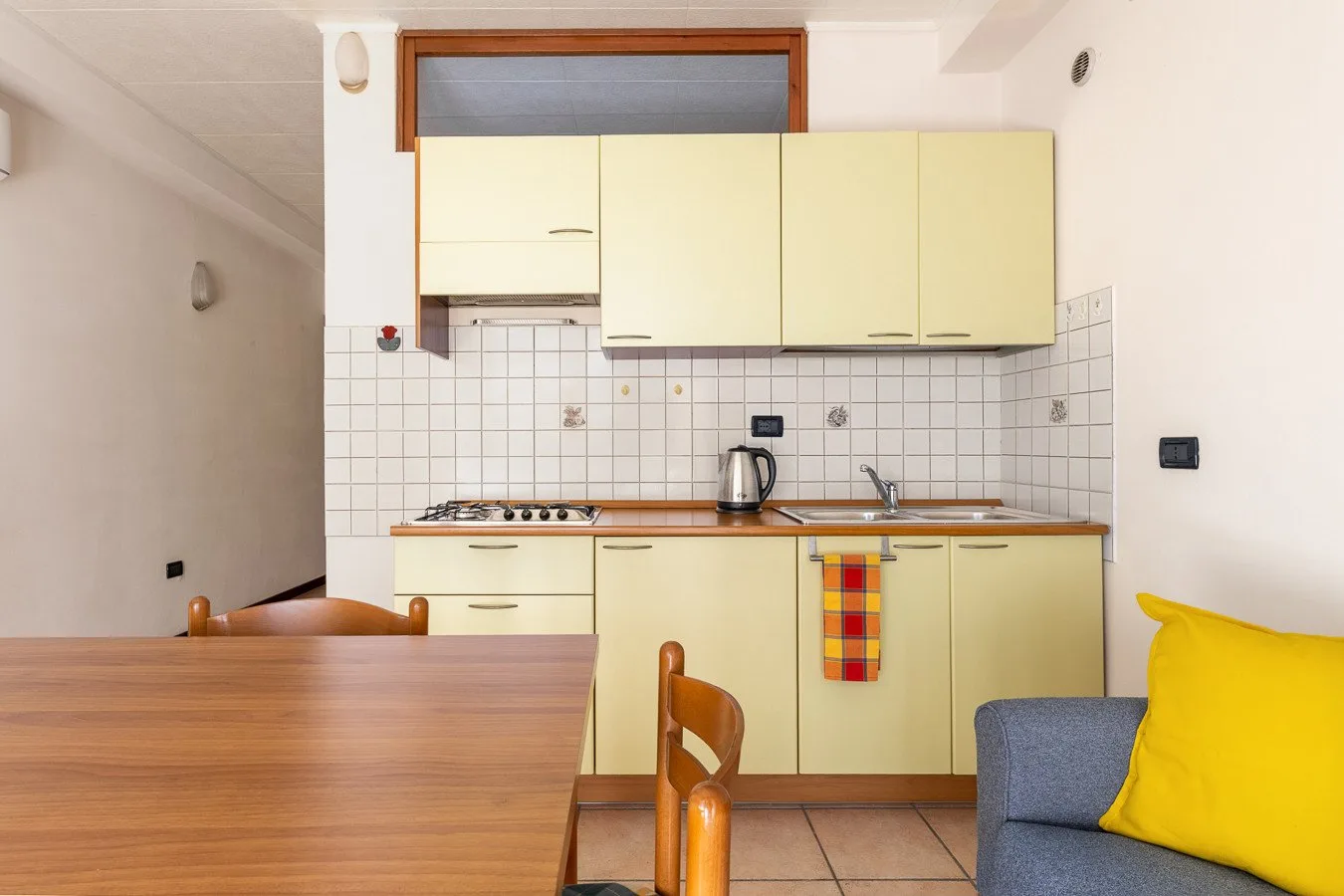 Una cocina con gabinetes claros, un salpicadero de azulejos y una mesa de comedor de madera.