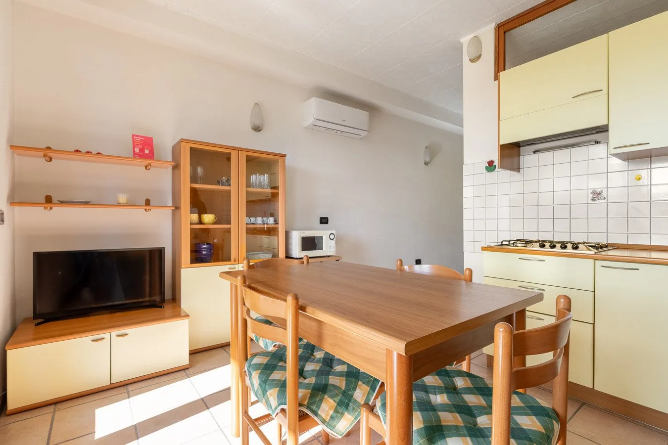Comedor con mesa y sillas de madera junto a una cocina compacta.