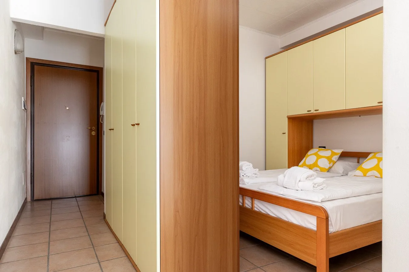 Un dormitorio con una cama y armarios empotrados junto a una entrada alicatada.