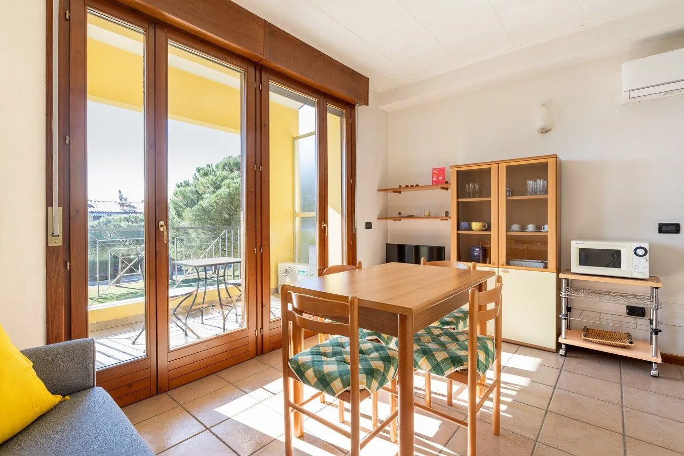 Un comedor luminoso con una mesa de madera junto a grandes puertas de vidrio que dan a un patio.