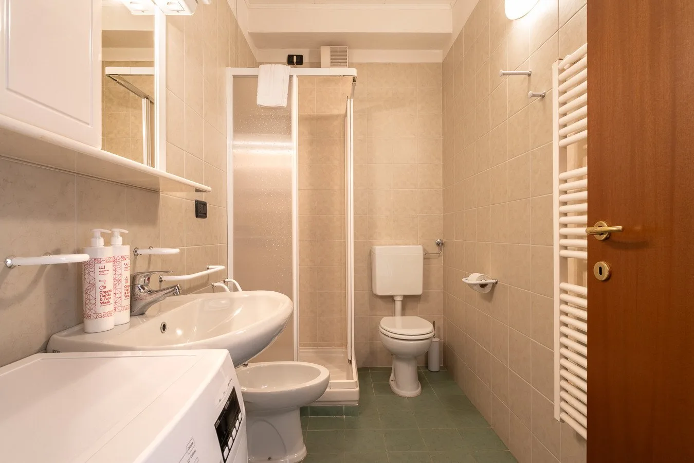 Un baño alicatado con lavabo, inodoro y ducha de vidrio.