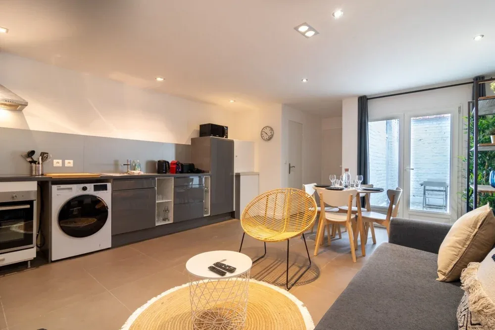 An open-plan kitchen and dining area with a table beside large windows.