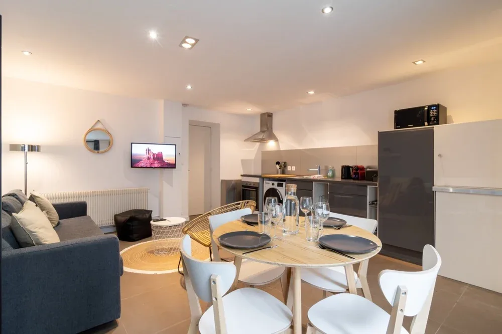 A dining area and kitchen with a set table and dark cabinetry.