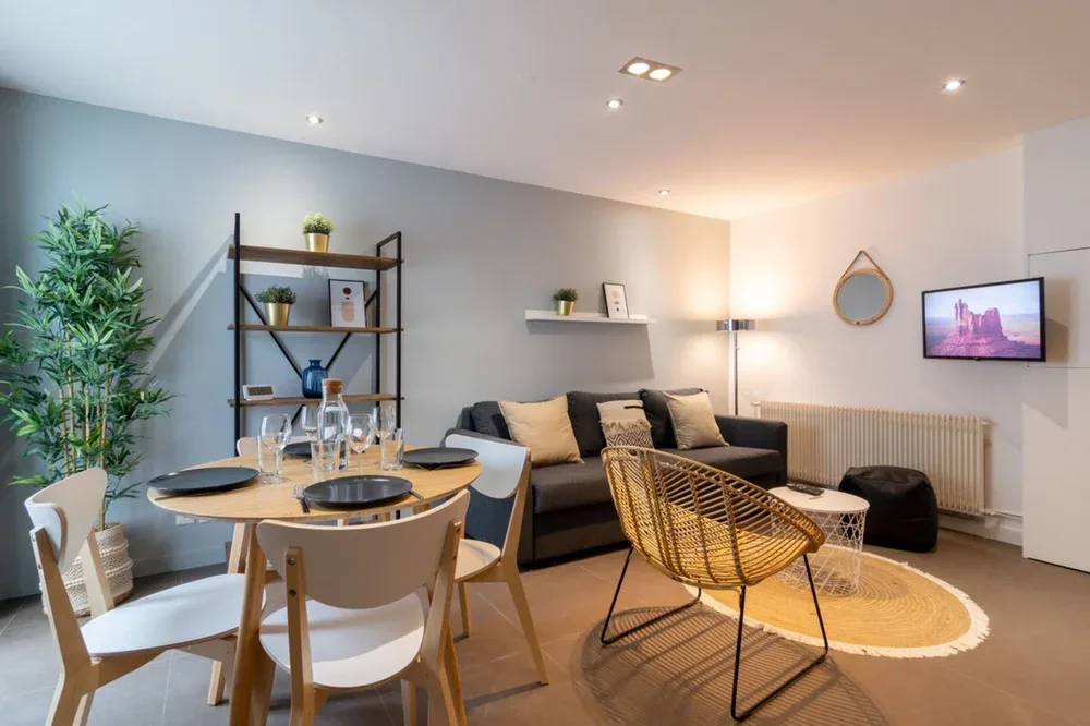 A living and dining area with a table, seating, and a wall-mounted television.