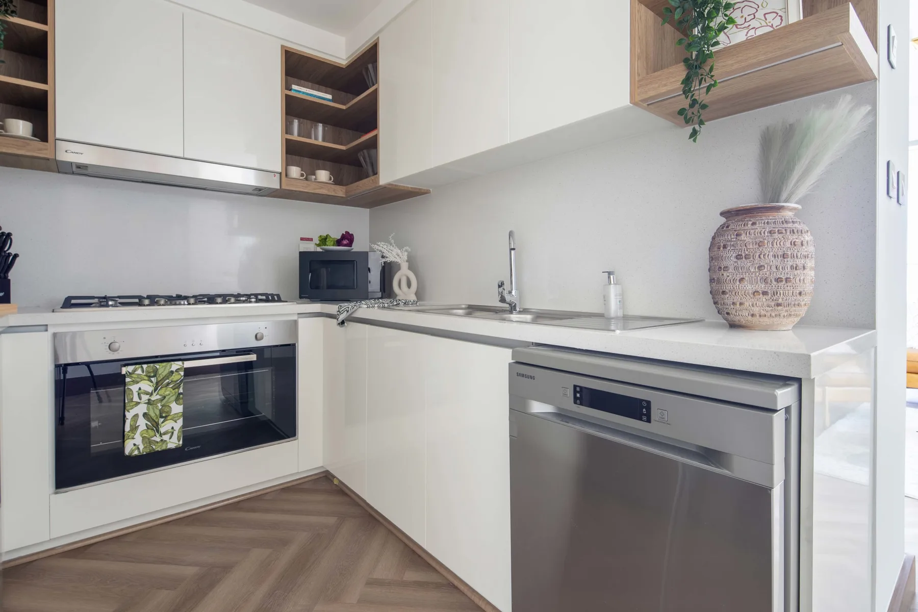 Una cocina moderna con gabinetes blancos, placa de cocina, horno y lavavajillas.