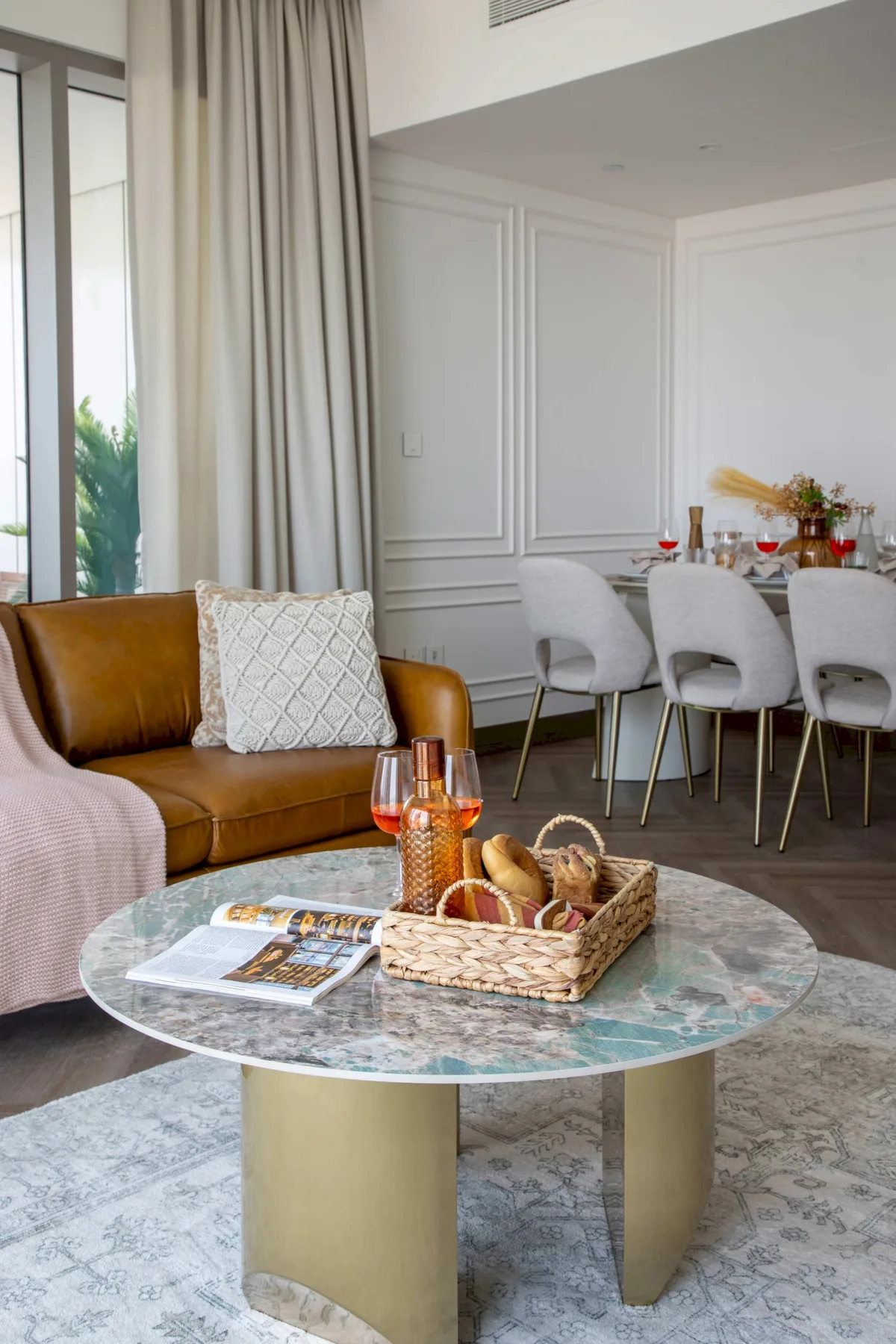 Sala de estar y comedor con un sofá de cuero y una mesa de centro redonda.