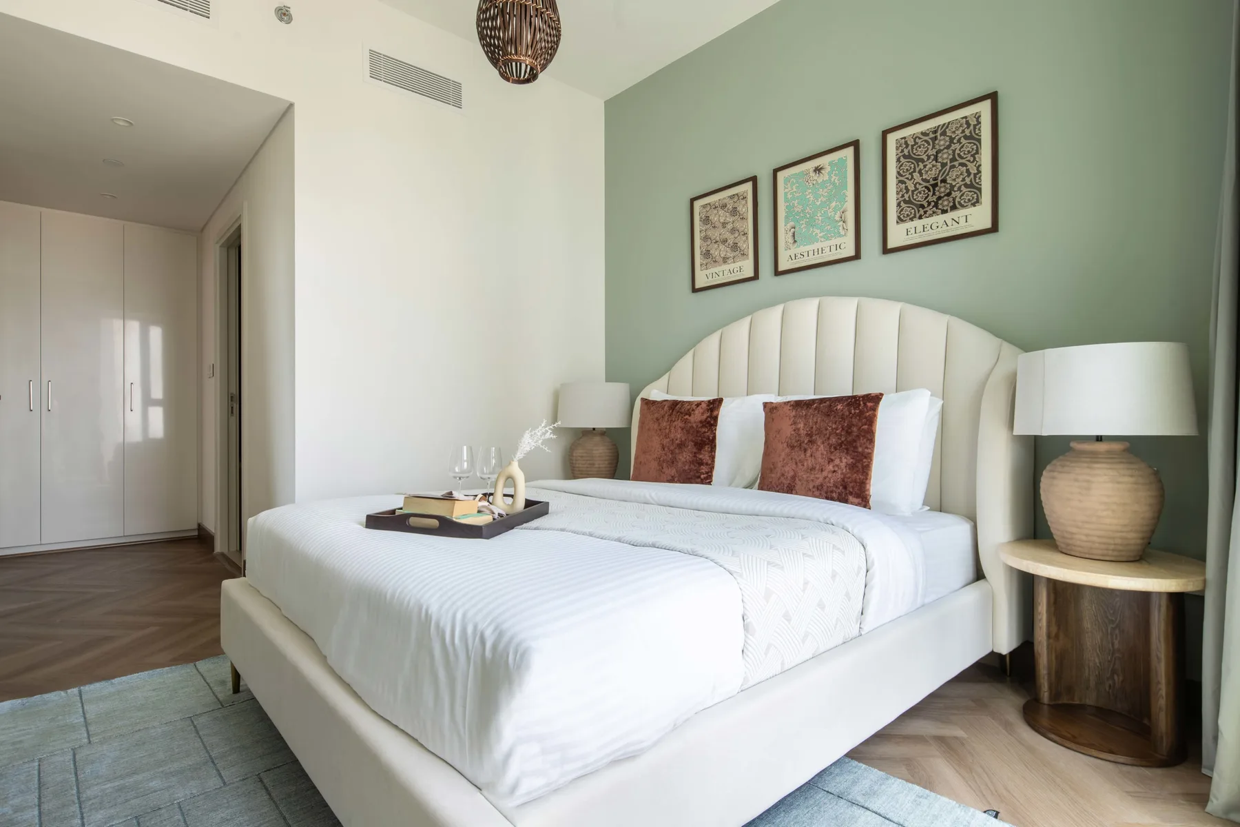 Un dormitorio con una cama bien tendida, mesas de noche y cuadros enmarcados.