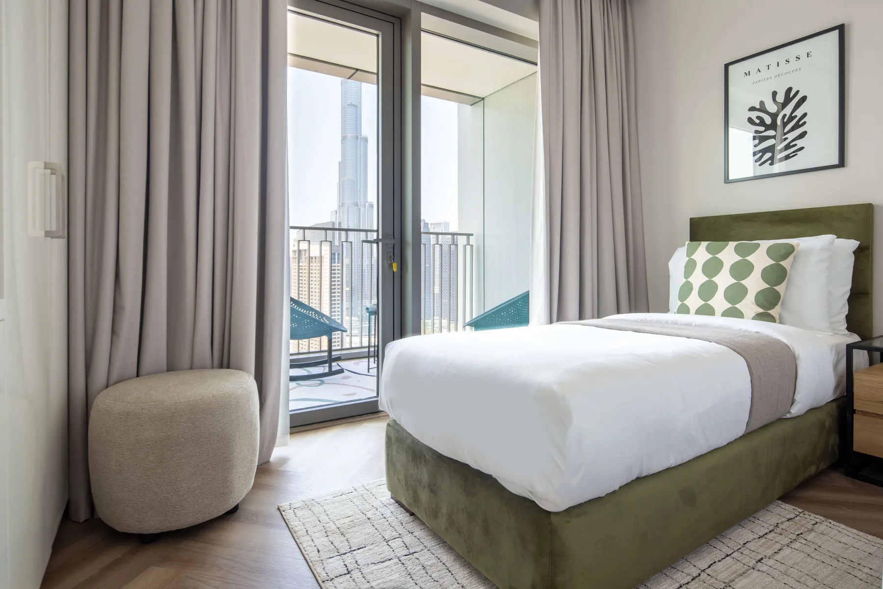 Un dormitorio con una cama tendida junto a ventanales y cortinas.