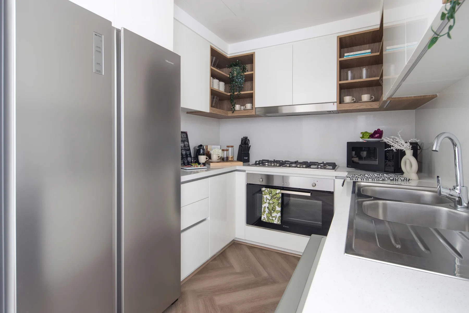 Una cocina moderna con gabinetes blancos, electrodomésticos de acero inoxidable y un fregadero.