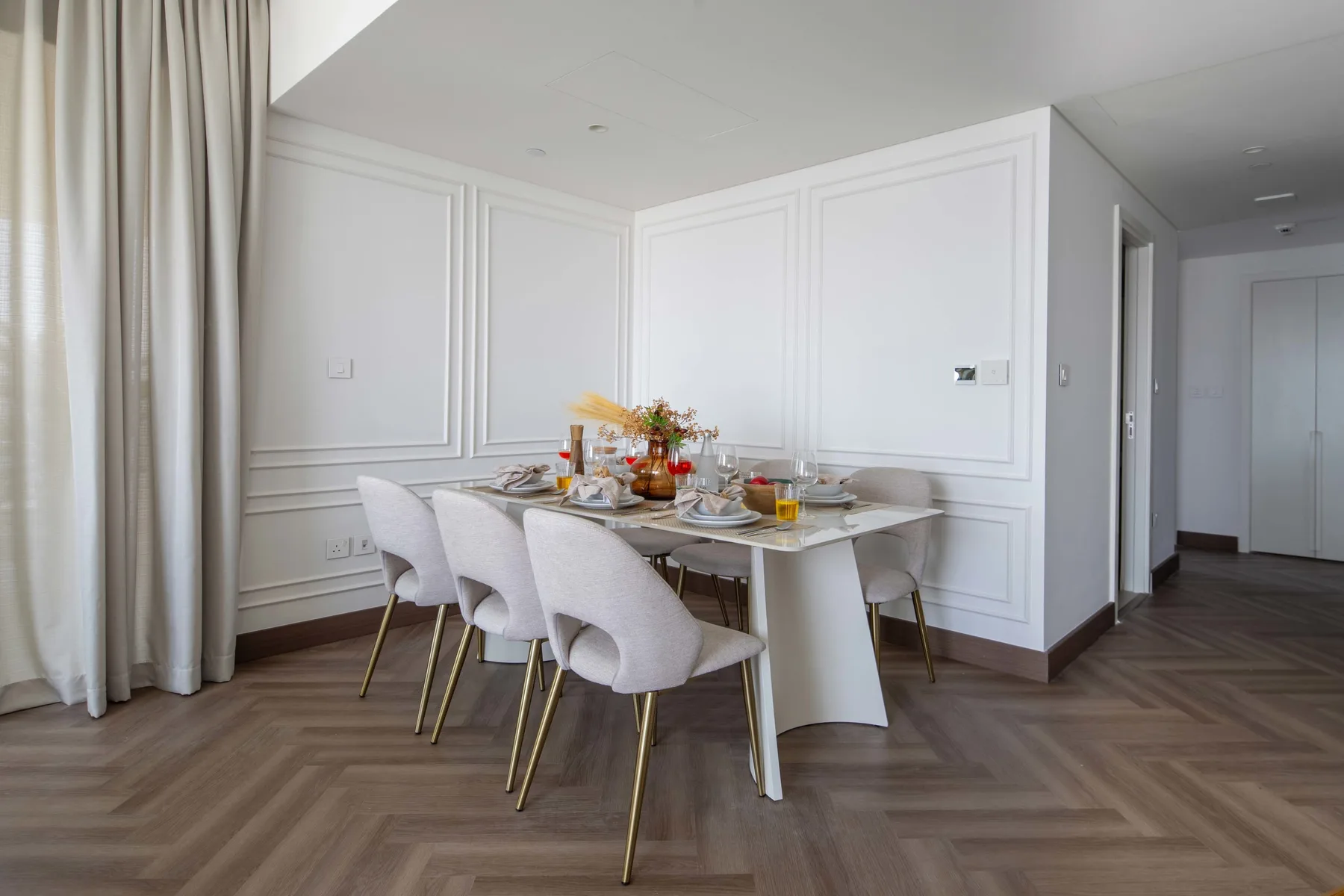 Comedor con una mesa puesta para comer junto a cortinas altas.