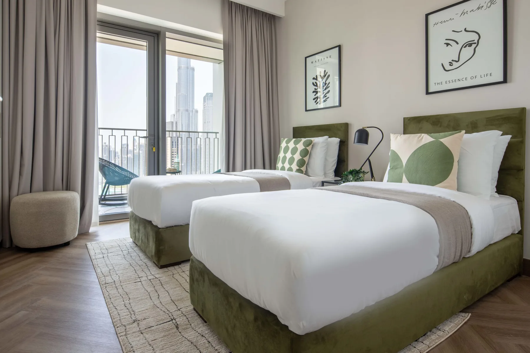 Un dormitorio con dos camas hechas y cortinas junto a una puerta de cristal al balcón.
