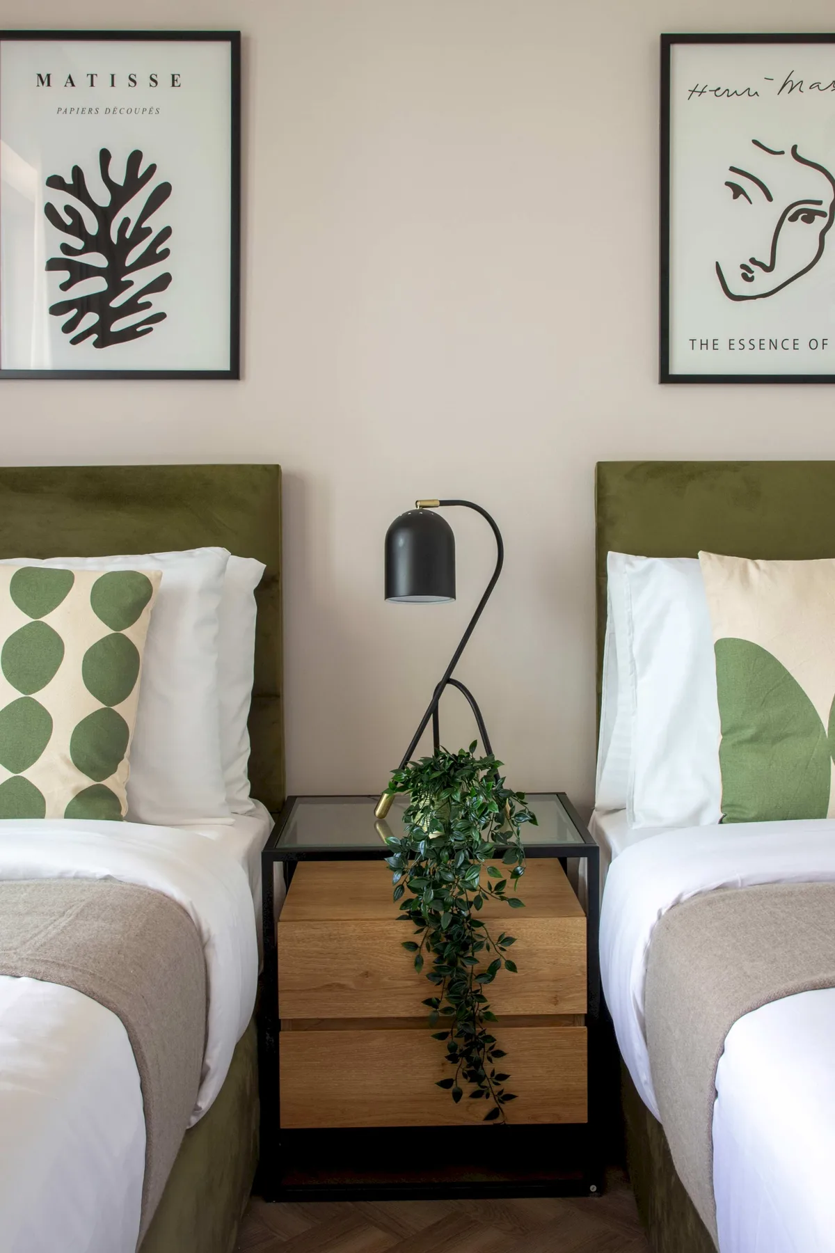 Un dormitorio con dos camas, una mesita de madera y cuadros en la pared.