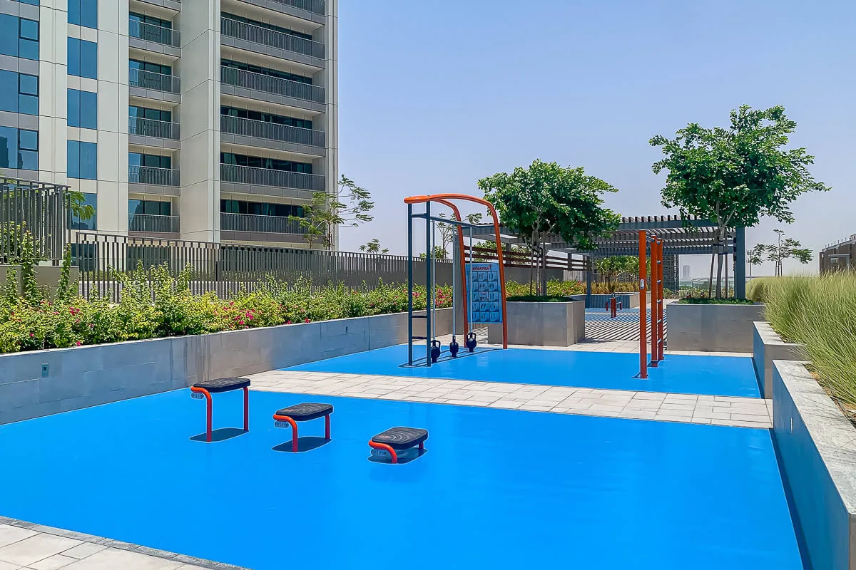 Un parque infantil al aire libre con una superficie azul brillante y juegos para trepar.