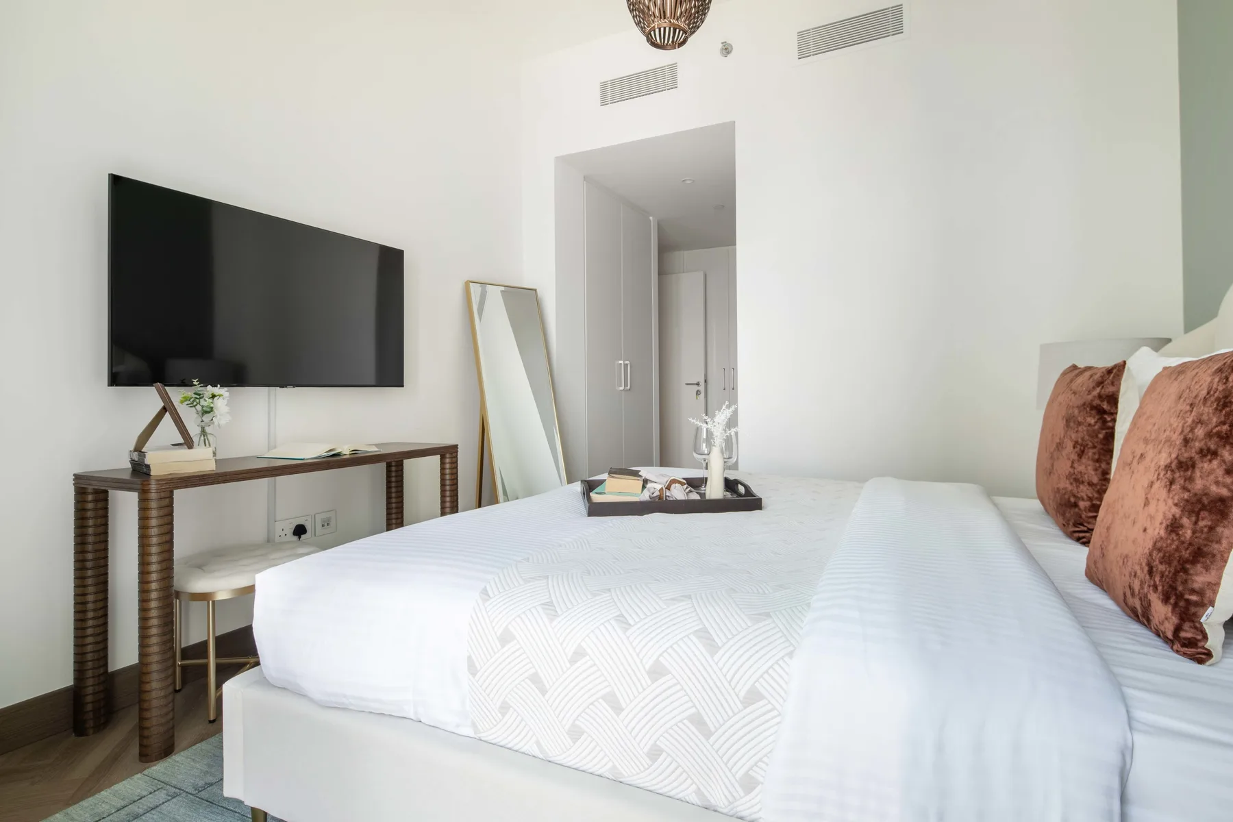 Un dormitorio con una cama bien tendida y un televisor montado en la pared.