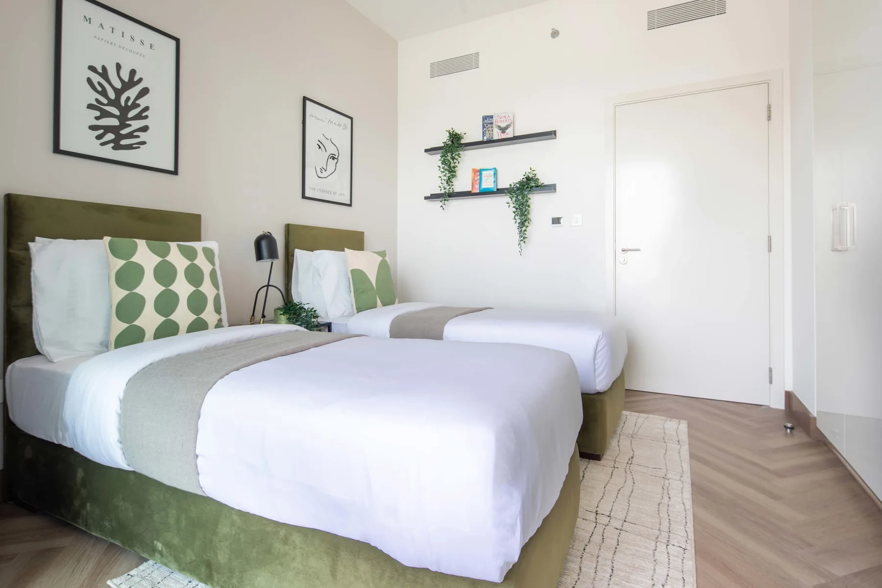 Un dormitorio luminoso con dos camas y pequeñas repisas en la pared.