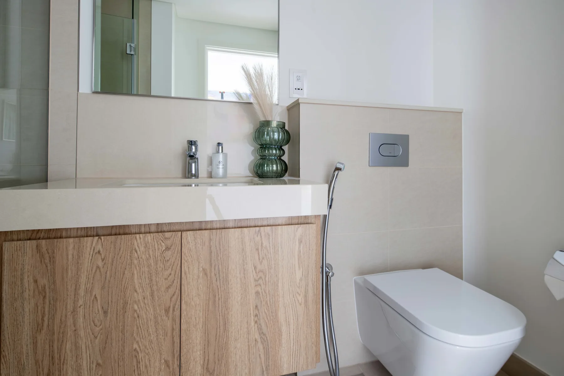 Un baño moderno con lavabo, mueble de frente de madera e inodoro.