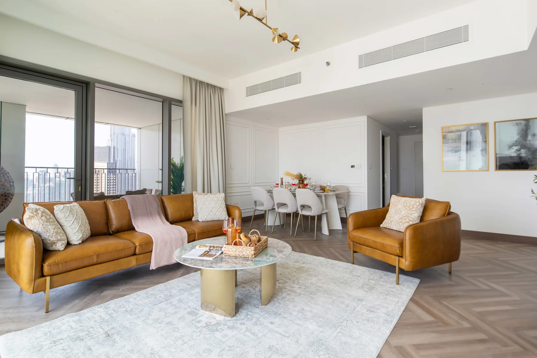 Una luminosa sala de estar con asientos, una mesa de centro y un comedor junto a las ventanas.