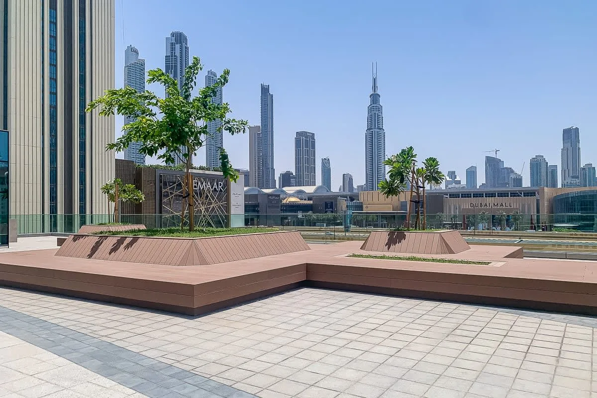 Una terraza pavimentada tiene jardineras elevadas y un horizonte urbano al fondo.