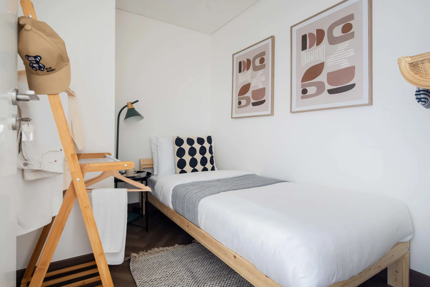 Un dormitorio con una cama tendida y cuadros enmarcados en la pared.