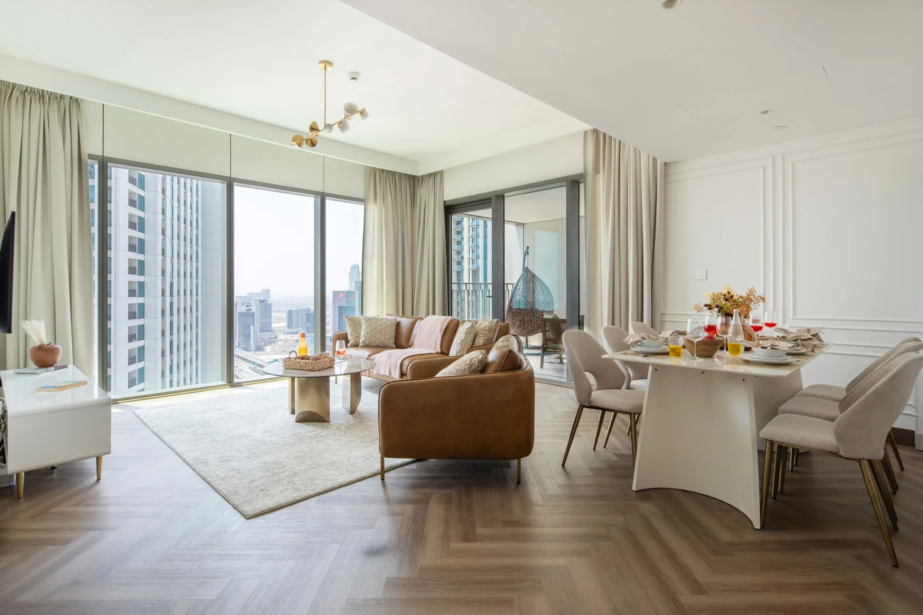Una luminosa sala de estar y comedor con grandes ventanas que dan a edificios de la ciudad.
