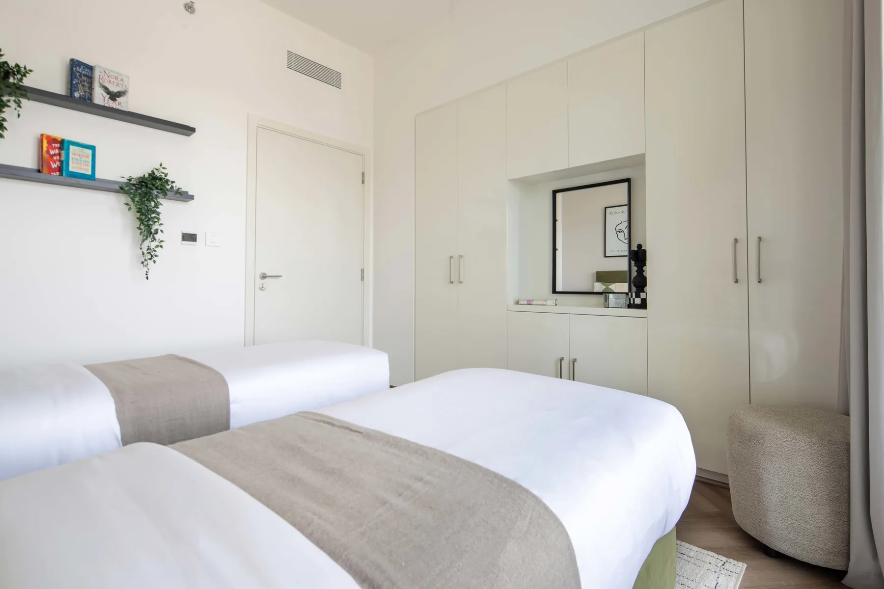 Un dormitorio luminoso con ropa de cama blanca y armarios empotrados en la pared.