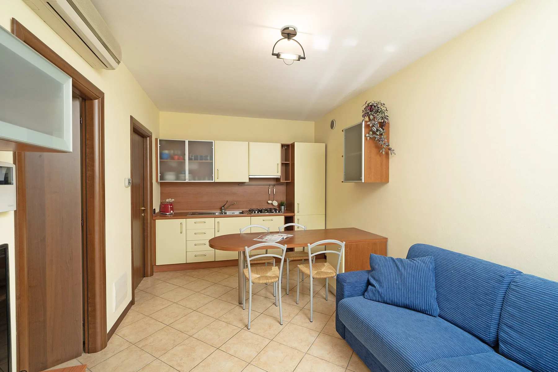 A kitchen and dining area with a table and blue seating.