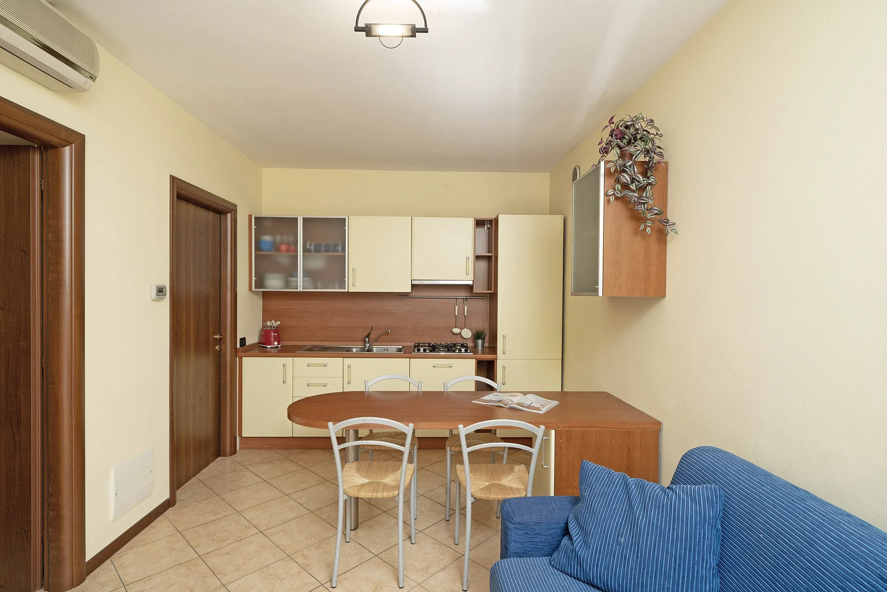 A kitchen and dining area with a table beside a blue seating area.