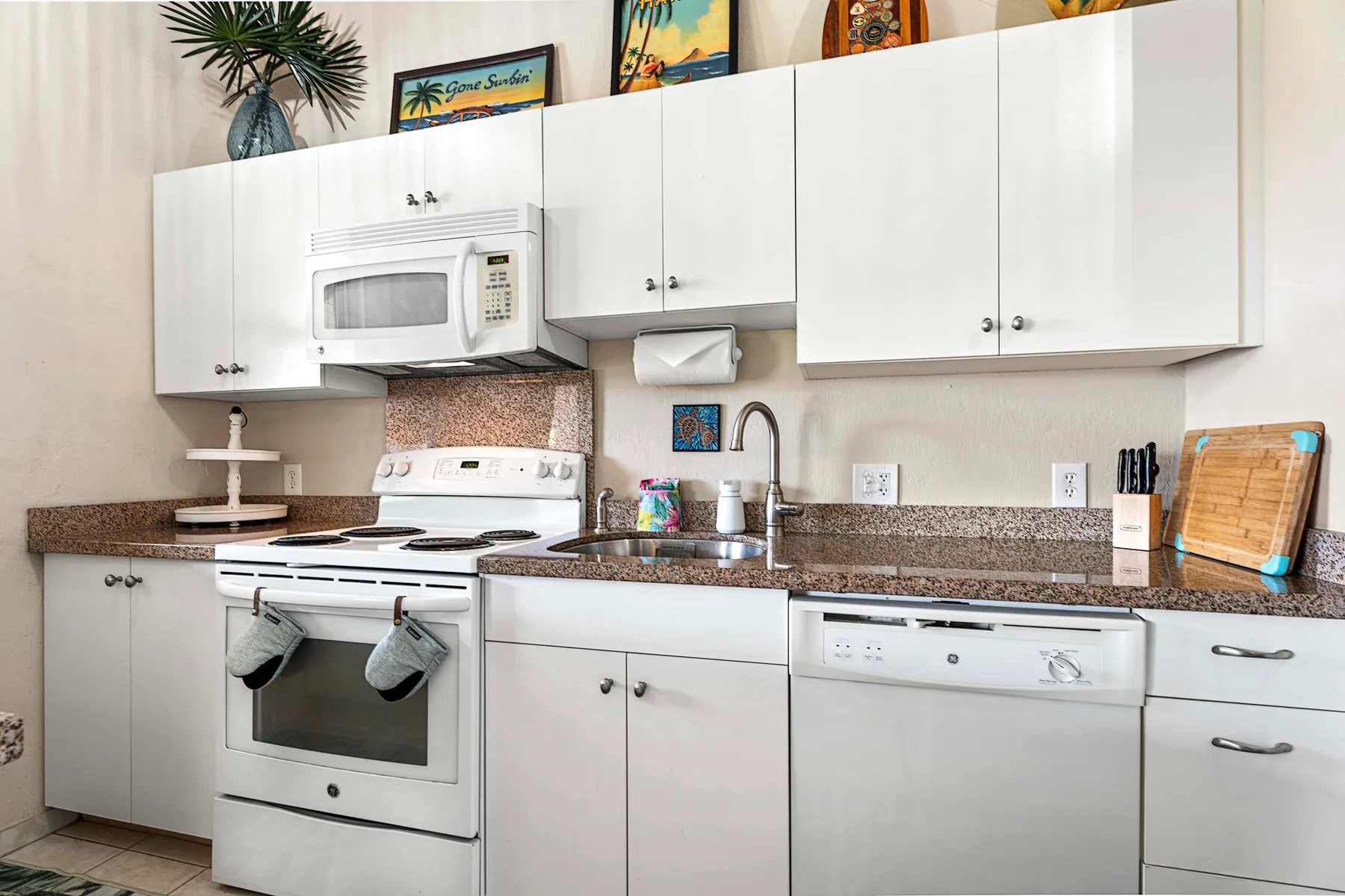 Una cocina luminosa con gabinetes blancos, una estufa y un fregadero.
