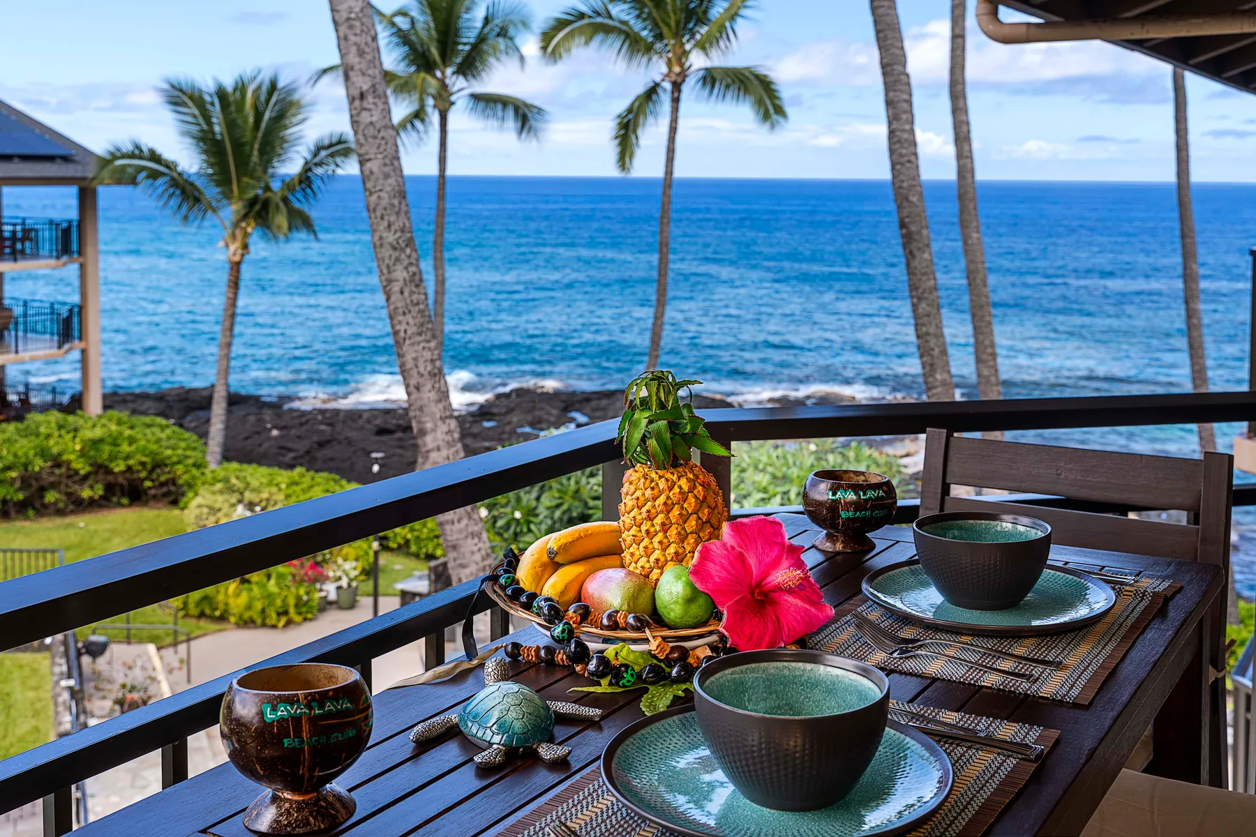 Una mesa de comedor al aire libre con fruta tropical tiene vistas al océano.