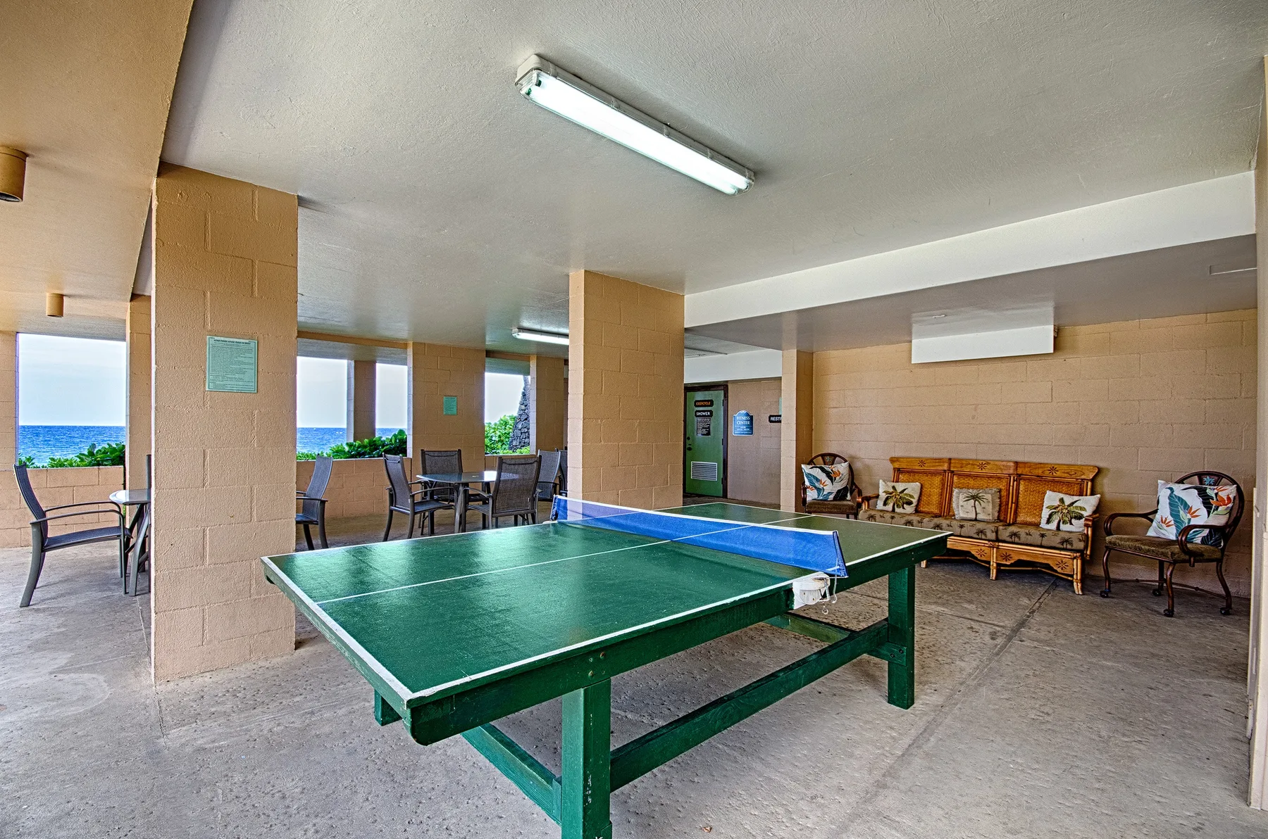Una zona recreativa cubierta con una mesa de ping-pong verde y asientos.