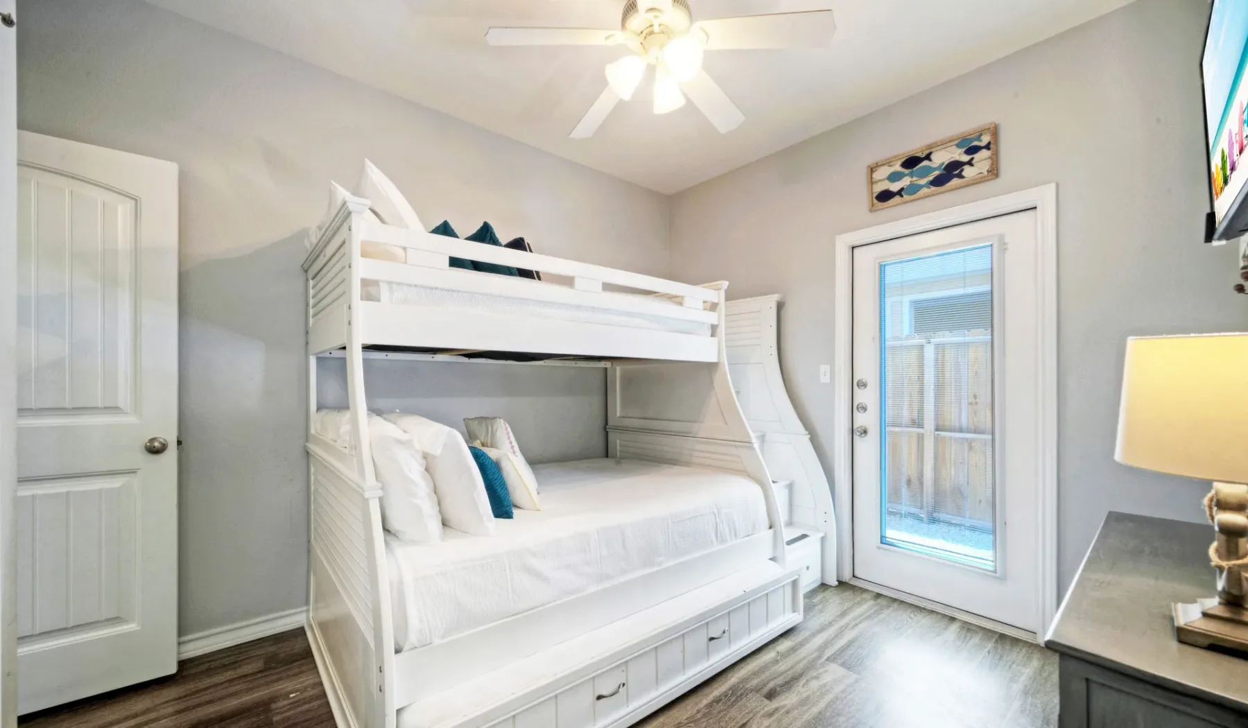 Un dormitorio luminoso con una litera blanca y una puerta exterior con panel de vidrio.