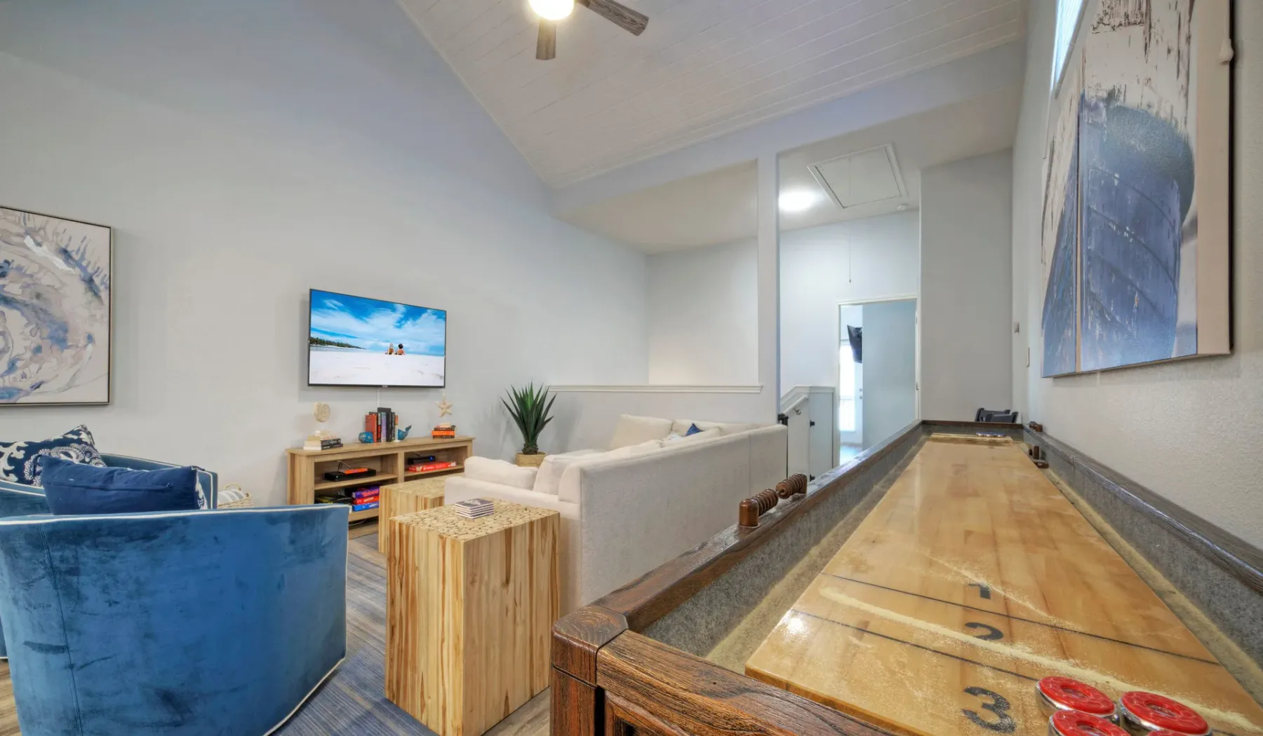 Una luminosa sala de estar con un sillón azul, asientos y una mesa de juegos de madera.