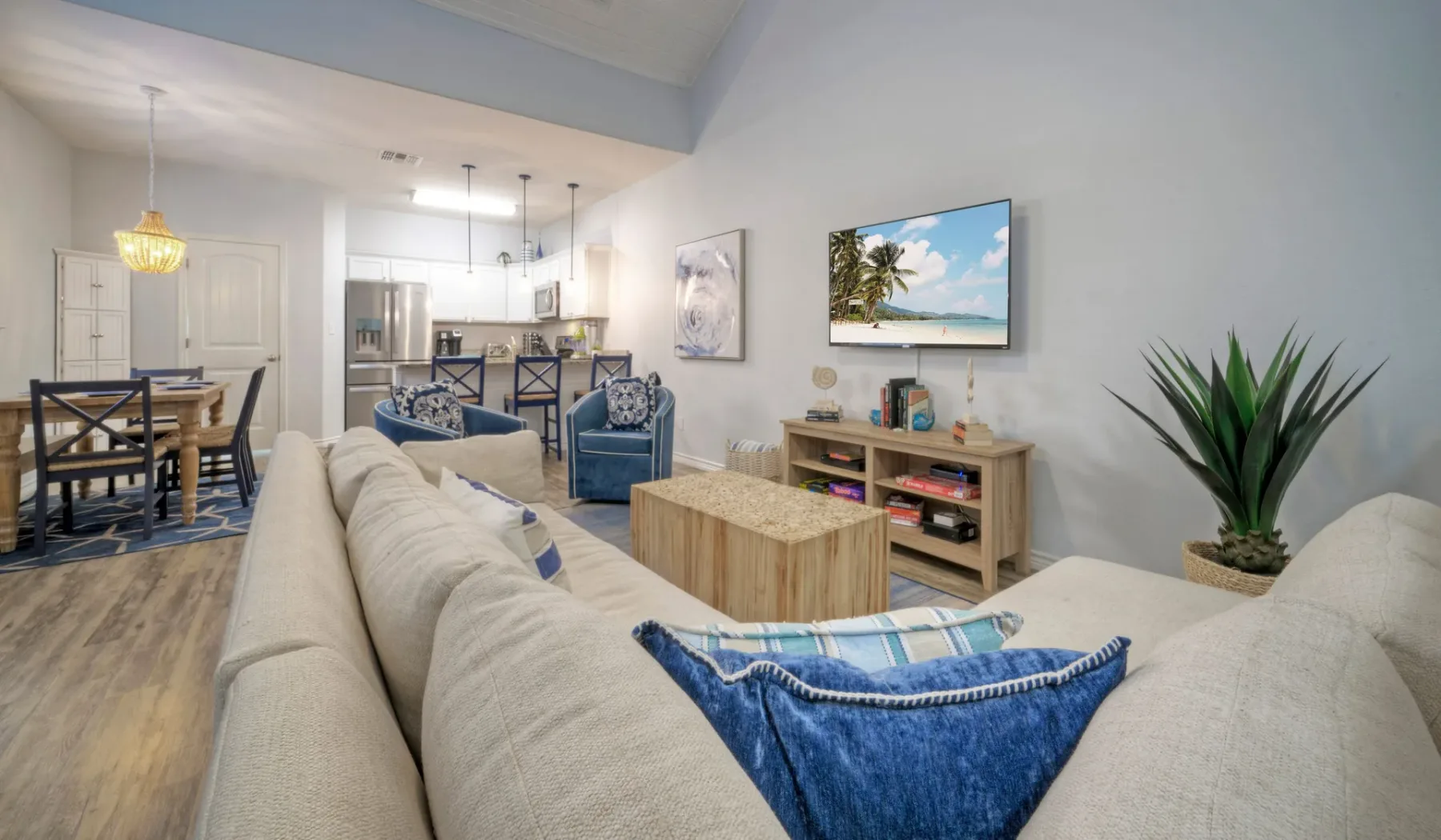 Una sala de estar con televisión, asientos y un comedor abierto.