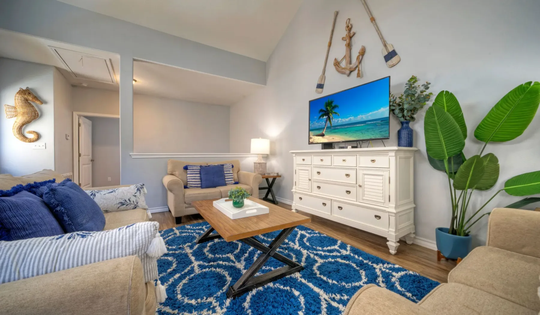 Una sala de estar con asientos, un televisor y una alfombra azul estampada.