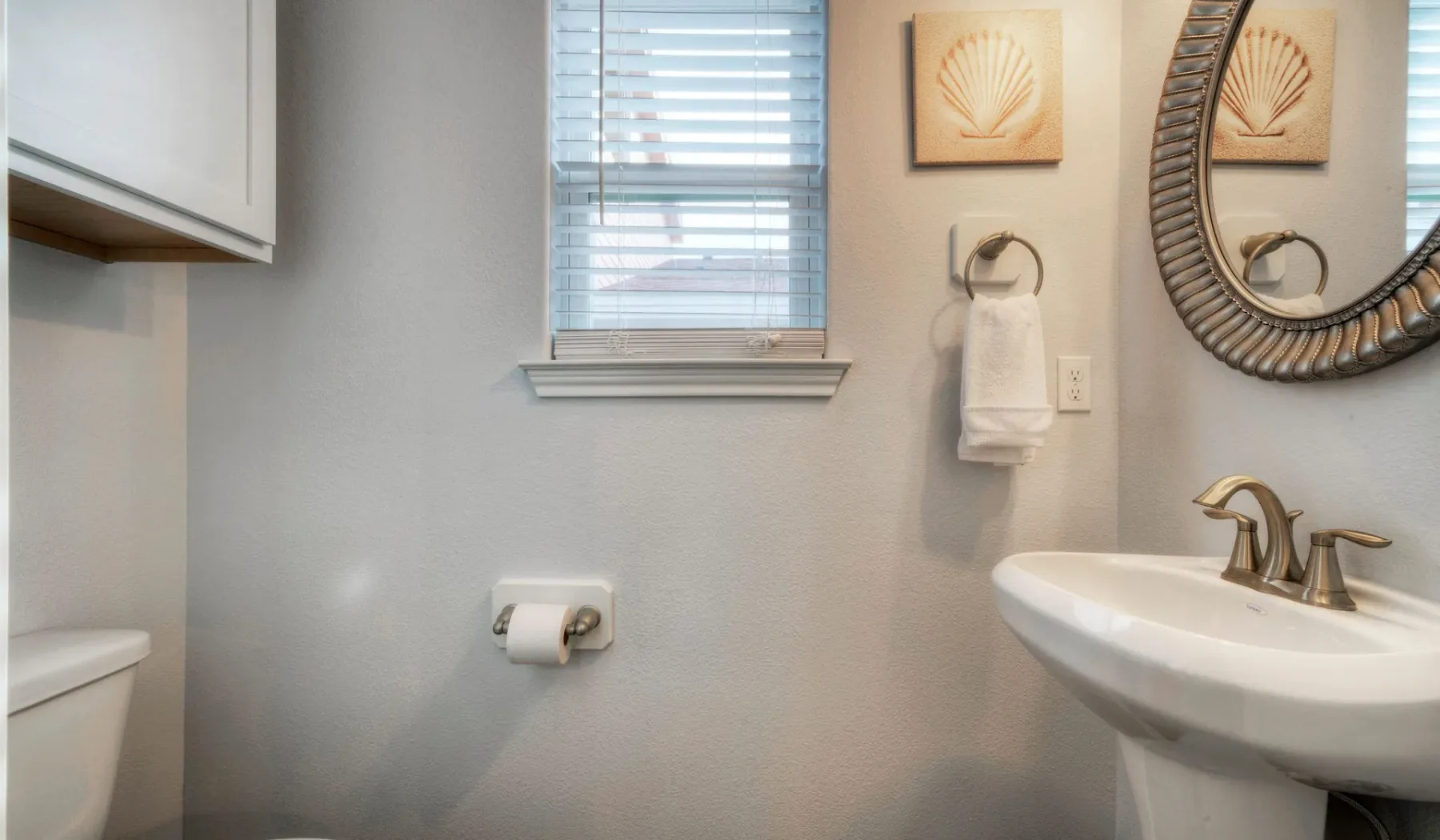 Un baño pequeño con lavabo, espejo de pared y ventana.