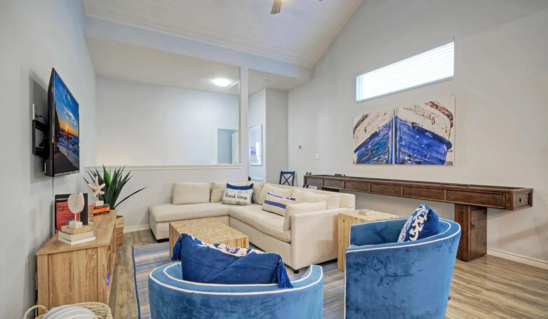 Una sala luminosa con asientos color crema, sillones azules y arte en las paredes.