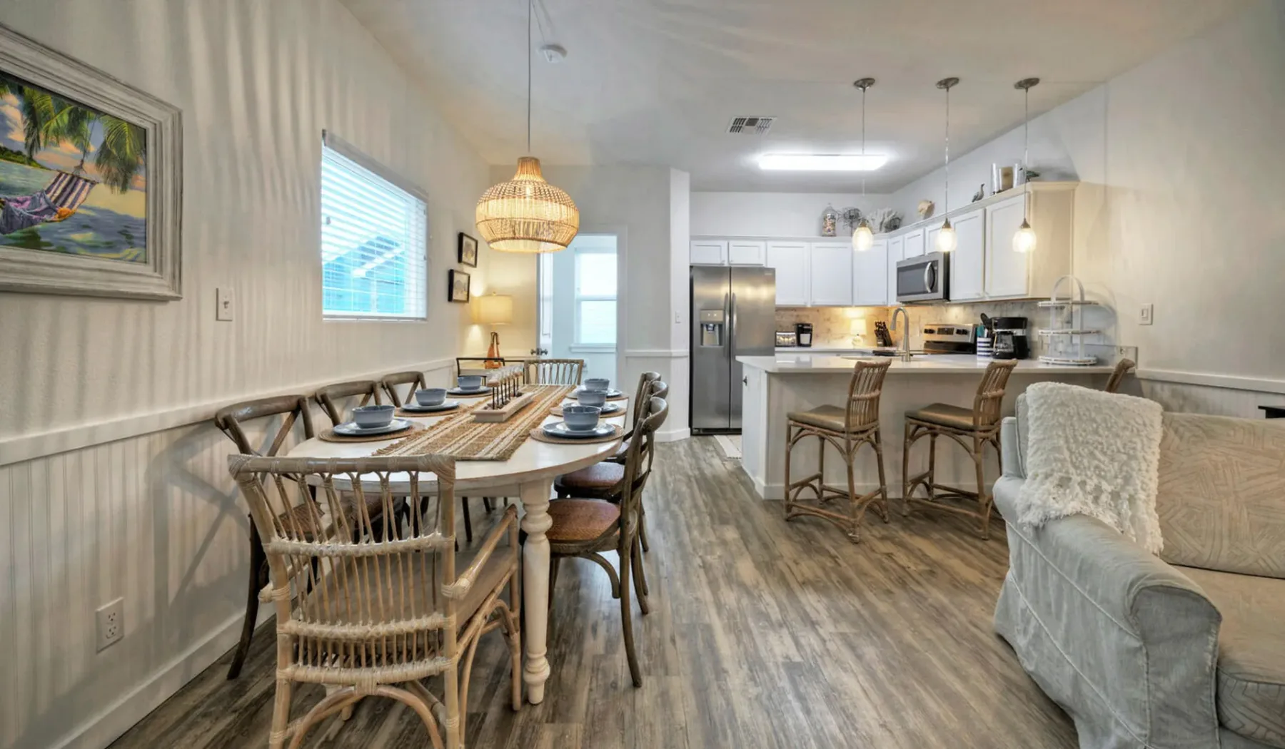 Un comedor y cocina abiertos, con una mesa puesta y una barra.