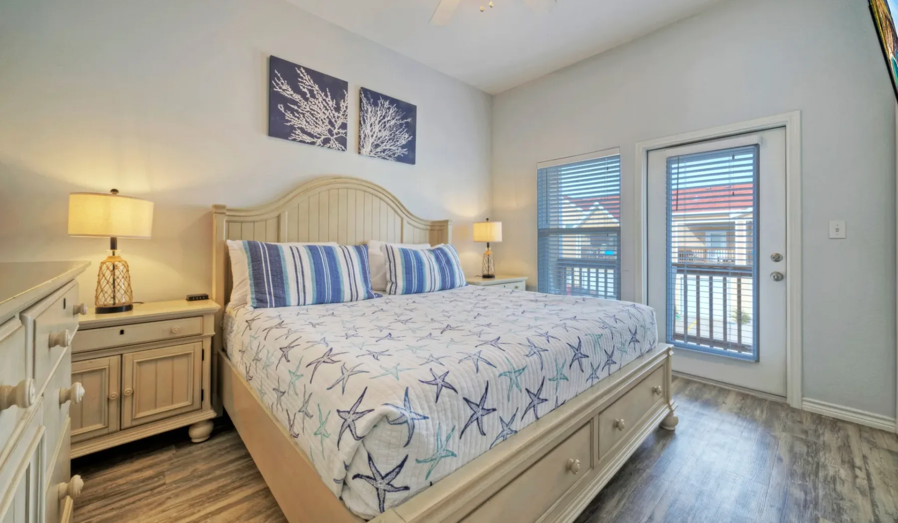 Un dormitorio luminoso cuenta con una cama grande y ropa de cama estampada en azul y blanco.