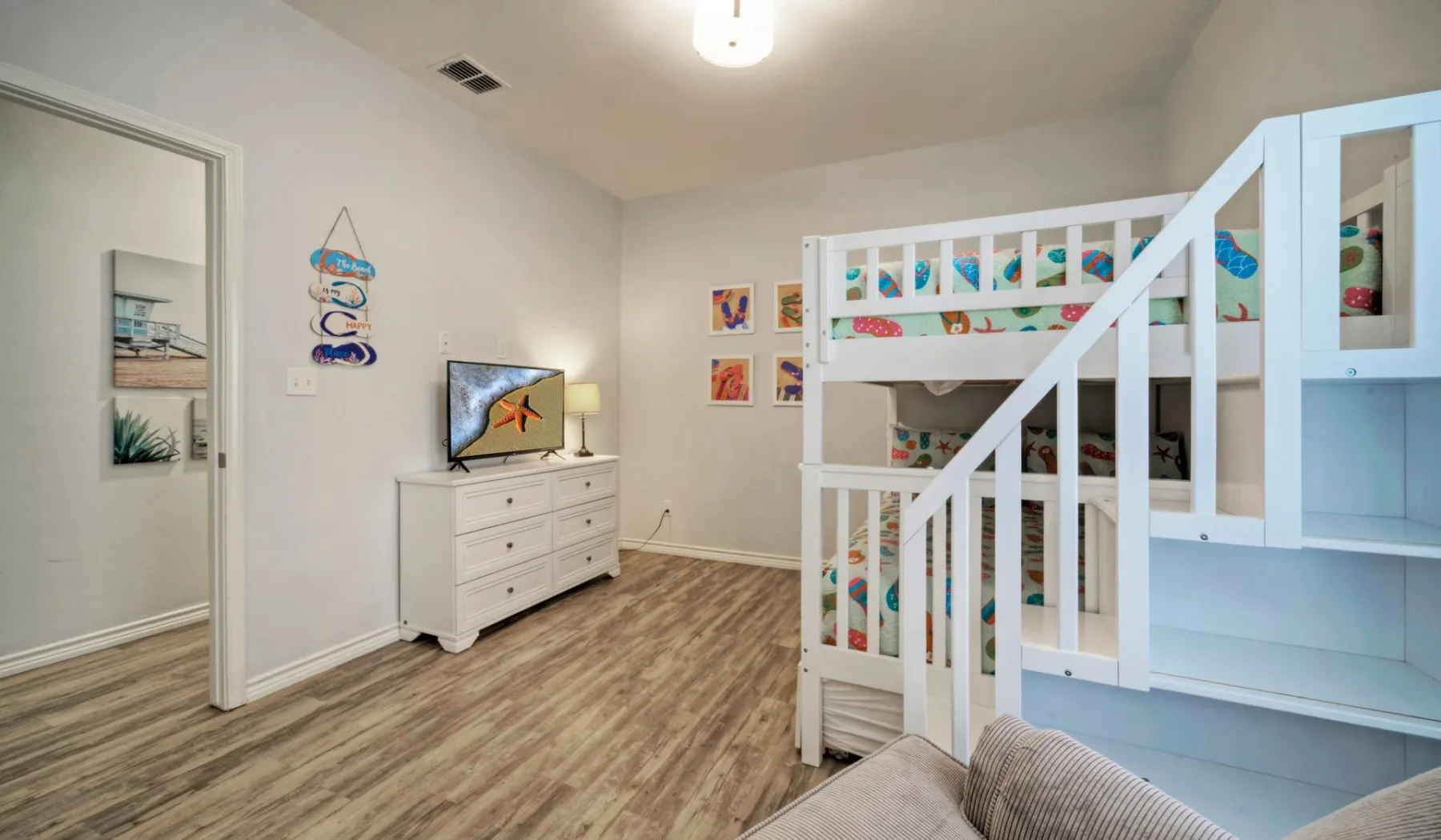 Un dormitorio luminoso con una litera blanca y una cómoda.
