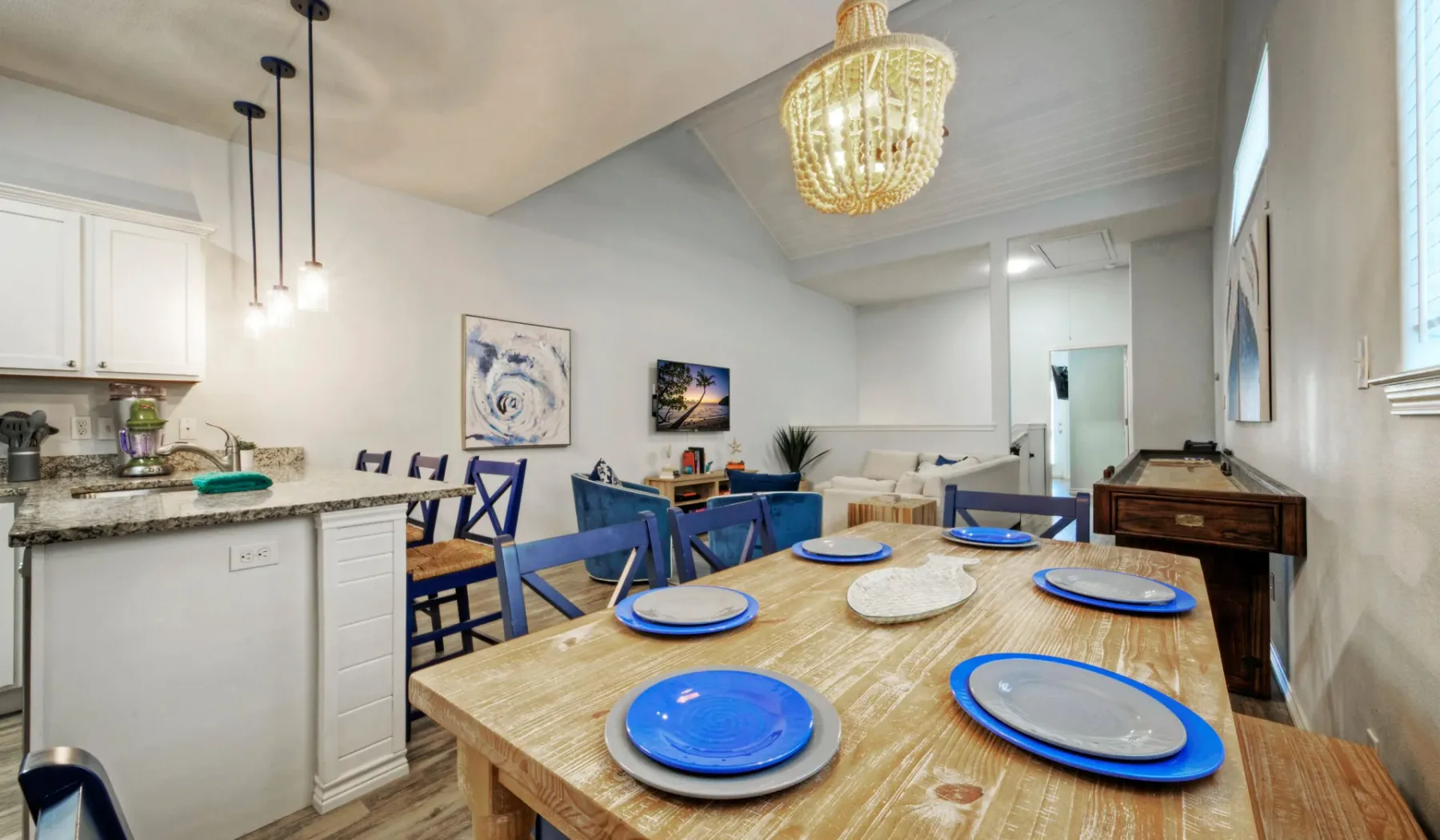 Comedor con una mesa de madera puesta con platos de borde azul y asientos cercanos.
