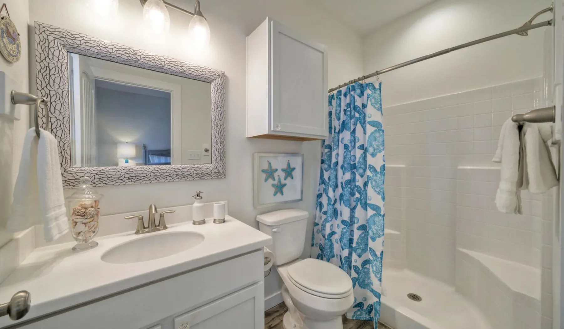 Un baño con lavabo, inodoro y una cortina de ducha azul estampada.