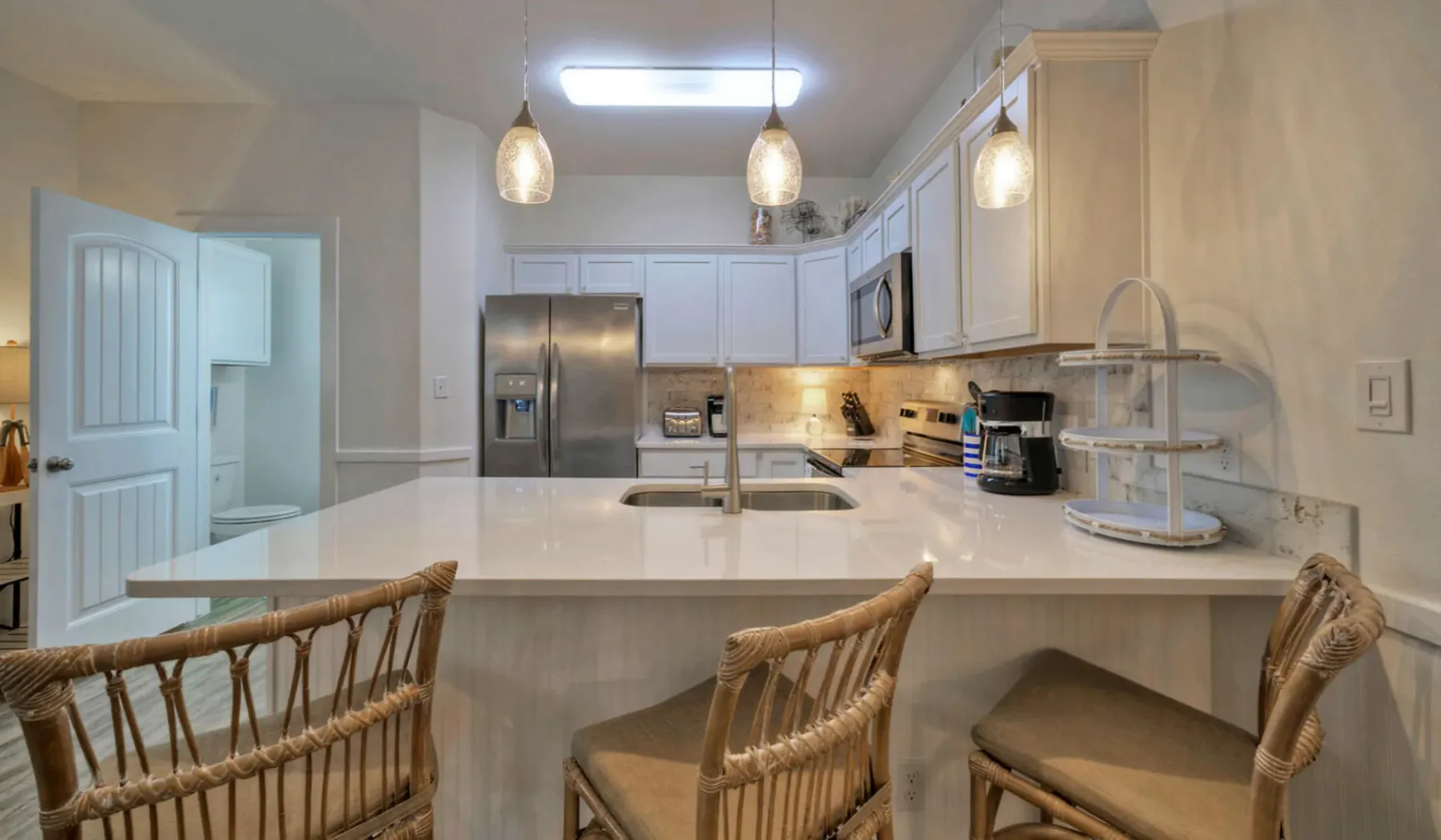 Una cocina luminosa con una isla grande y gabinetes claros.