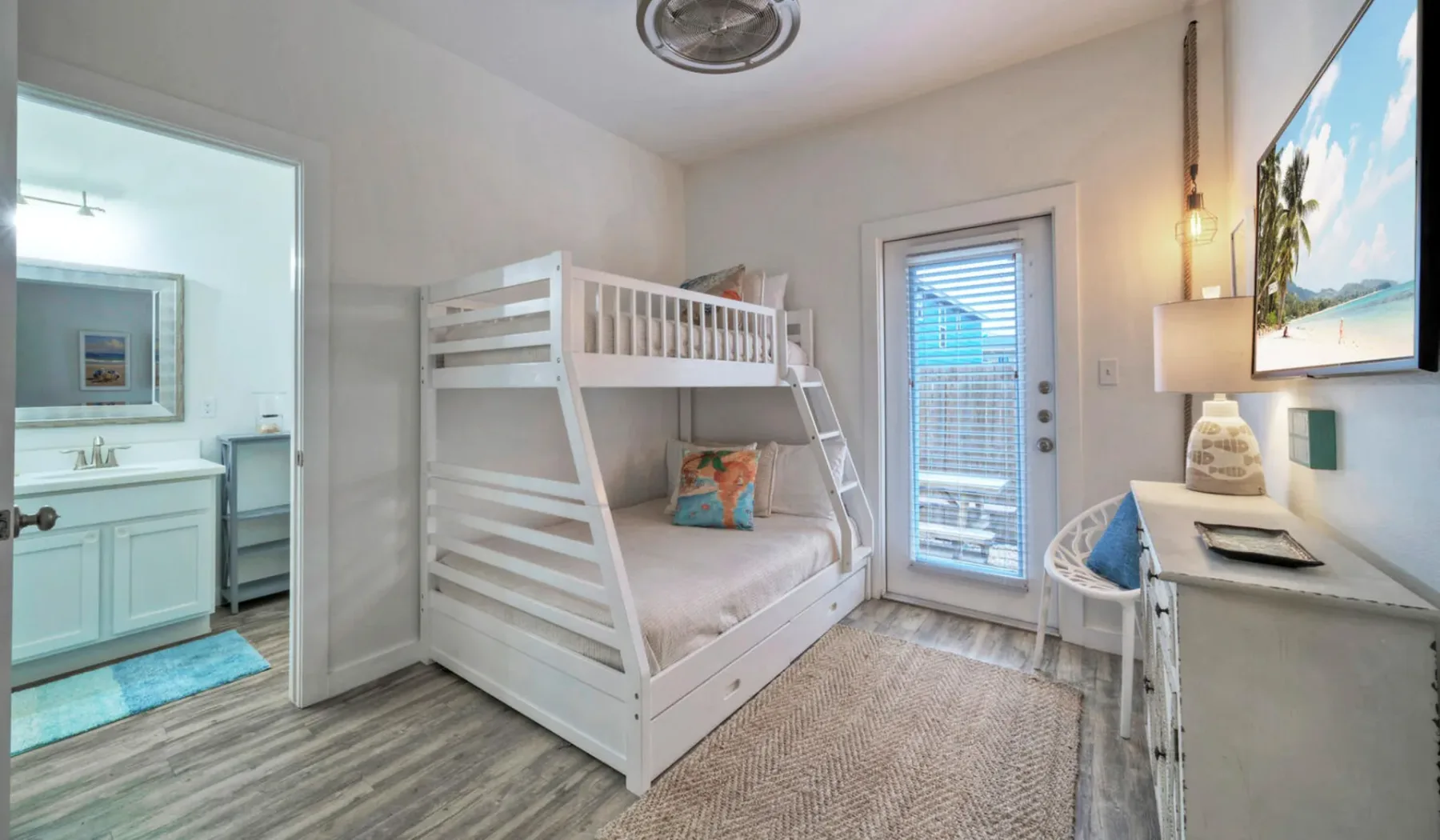 Un dormitorio con una litera blanca y una puerta hacia un baño.