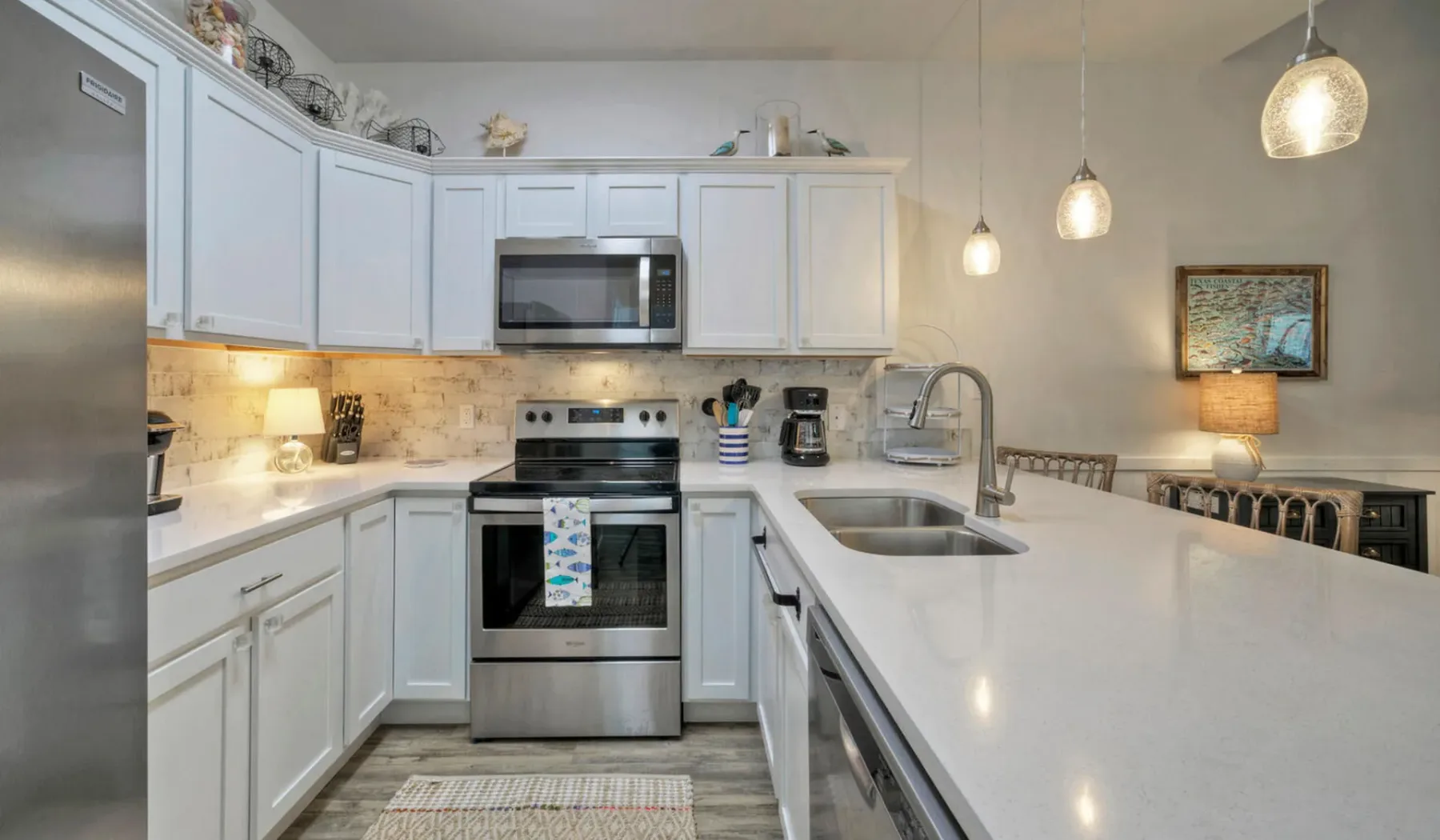 Una cocina luminosa con gabinetes blancos, electrodomésticos de acero inoxidable y una isla grande.