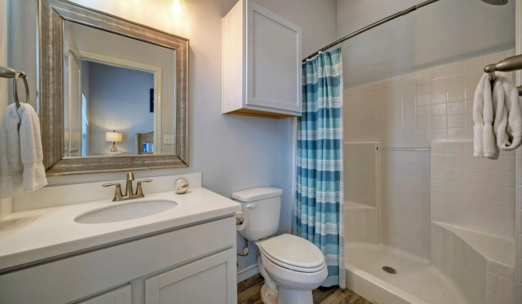 Un baño con lavabo, inodoro y ducha detrás de una cortina a rayas.